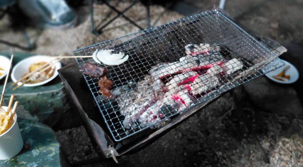 白く灰になった炭と奥でゆらめく炎。女子高生たちが散歩に出た後の寂しさを映すコンロ