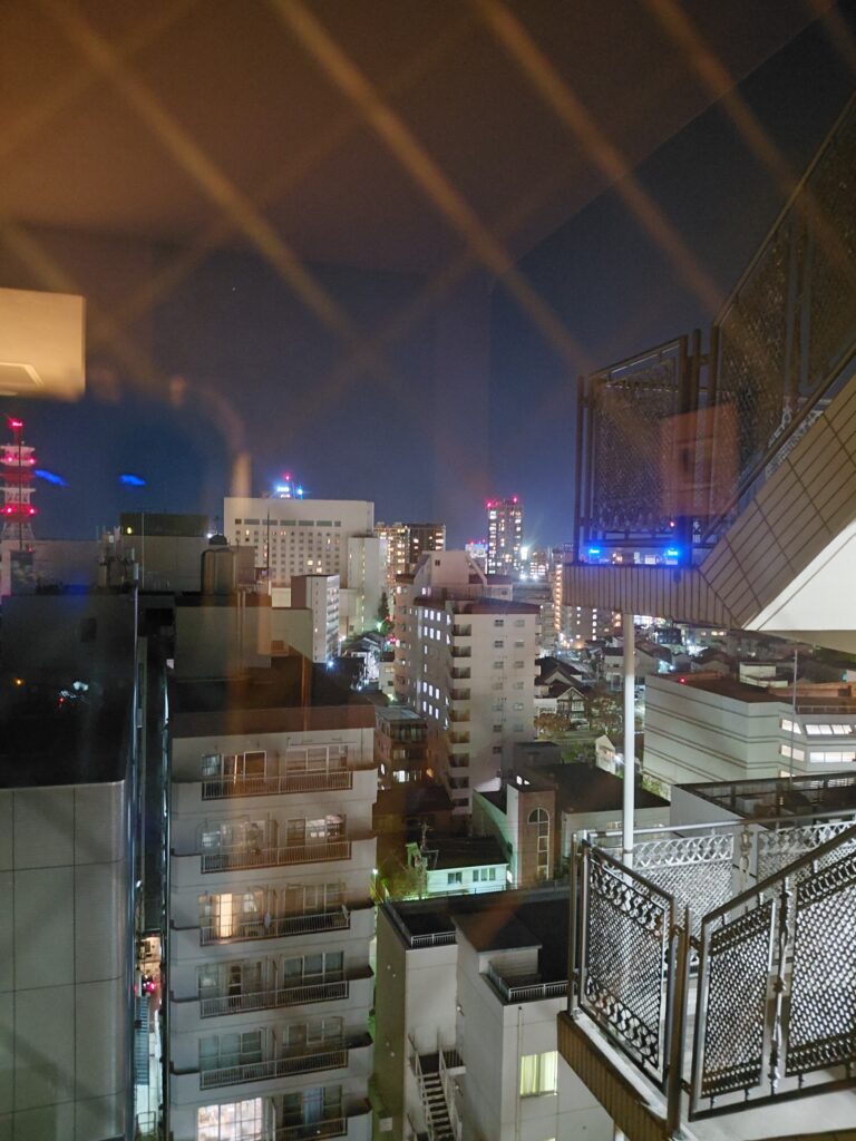 14階の客室から見た新潟市内の夜景。赤く光る電波塔が輝き、街の灯りが広がっている。