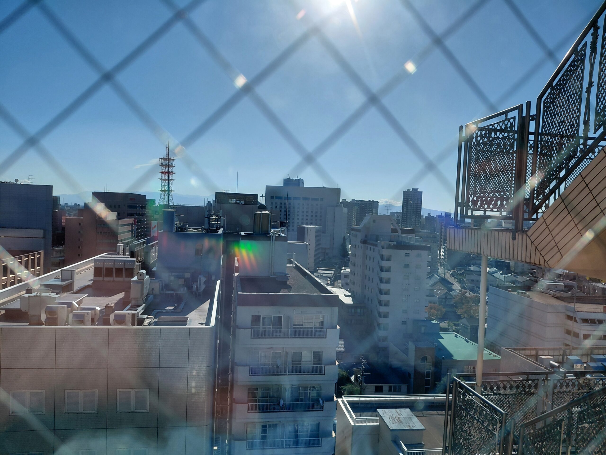 14階から見た新潟市内の朝の景色。青空とまぶしい朝日、広がる市街地が清々しい。
