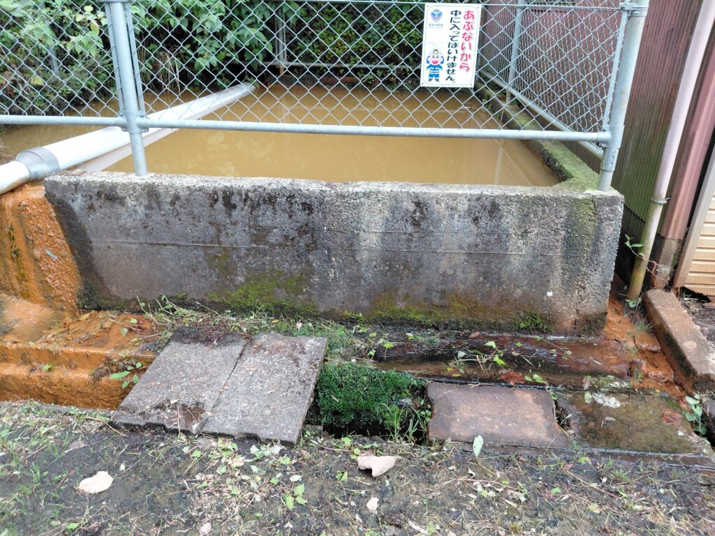 防火水槽全体とあふれ出した茶色い水