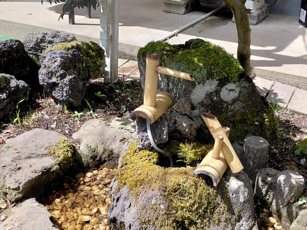 苔むした石と竹で作られた鹿威し（ししおどし）。庭の水が流れ、和の雰囲気を演出している。