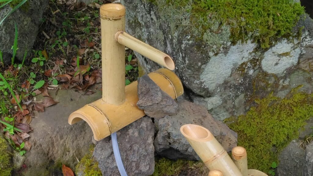 巻の家の庭にある竹のししおどし（飾り）と苔むした石の景観